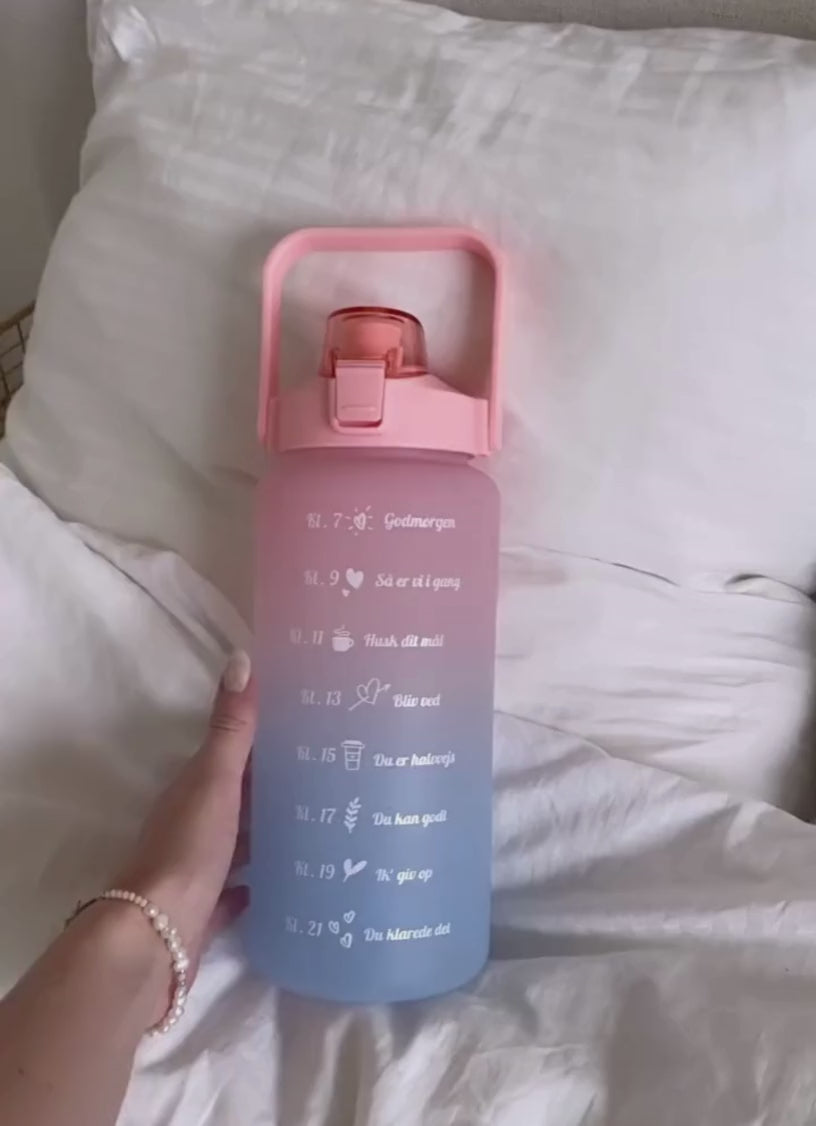2L motivationsvandflaske med tidspåmindelser. Smart vandflaske til voksne. Drikkeflaske med sugerør og one-click åbning. BPA-fri og 100 % tæt. Opvaskemaskinesikker drikkedunk. Vandflaske til arbejde, bil, fitness og hverdagsbrug. Hjælp til at drikke mere vand. Flaske med mål og tidsmarkering. Sund livsstil. Bedre hydrering. Populær drikkeflaske til kvinder og mænd. Smart Makro flaske. Stor vandflaske med motiverende design. dansk tekst.